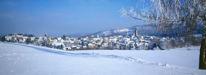 Snow covered landscape against blue sky