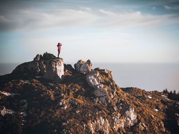 People standing on rock formation against sky