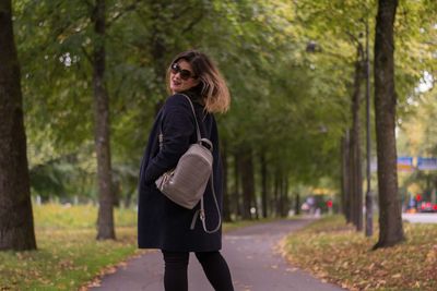 Side view of a smiling young woman against trees