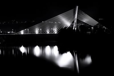 Illuminated suspension bridge over river at night