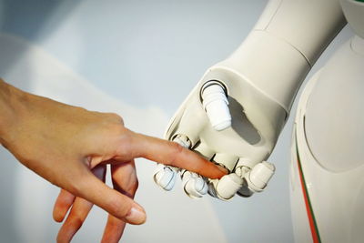 Cropped hand of woman touching robot