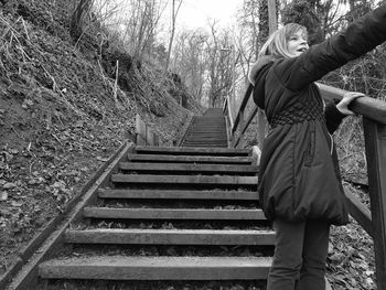 Low angle view of teenage girl standing on staircase in forest