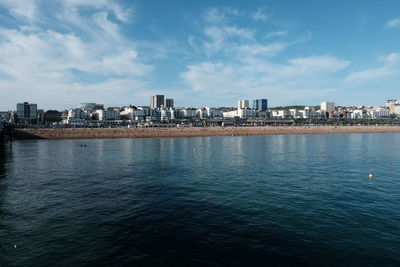 Buildings by river against sky