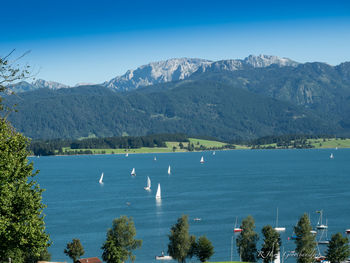 Scenic view of lake and mountains against clear blue sky