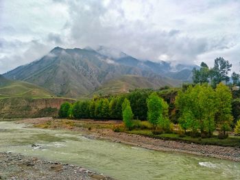 Scenic view of river by mountains against sky