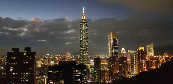 Illuminated buildings in city against sky at night