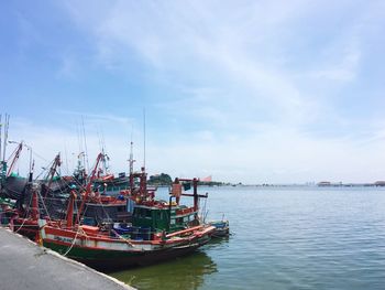 Boats moored at harbor against sky