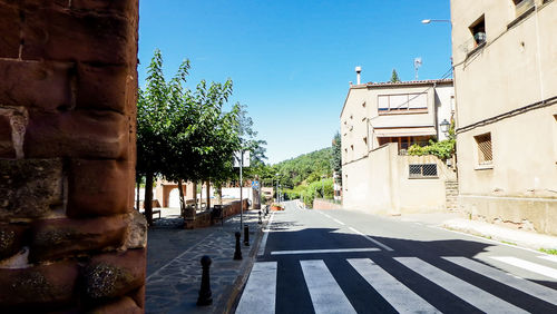 Alley amidst buildings in city against clear blue sky