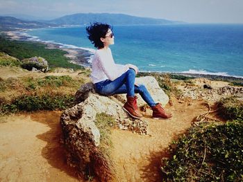 Young woman sitting on rock at beach