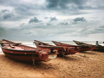 Boats in sea against cloudy sky