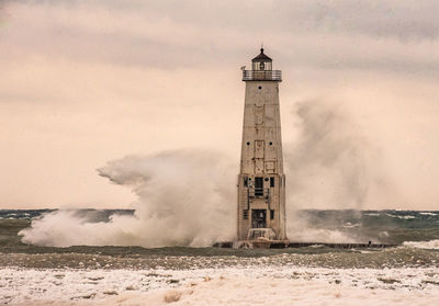 Lighthouse by sea against sky