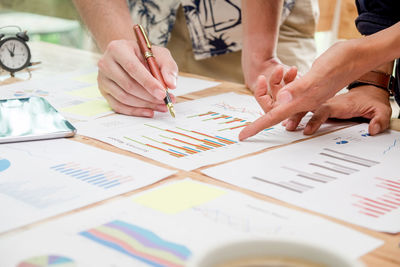 Cropped hands business people discussing graphs at desk in meeting