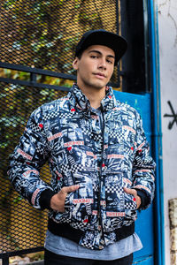 Young man looking away while standing against wall