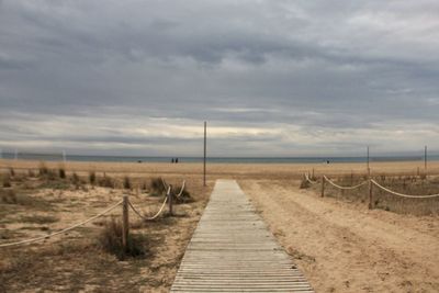 Empty boardwalk on beach against sky