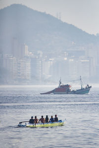 People on boat in sea against sky