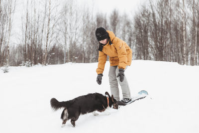 A girl plays with a corgi dog in a winter park