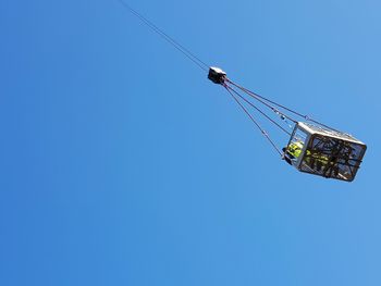 Low angle view of ski lift against blue sky