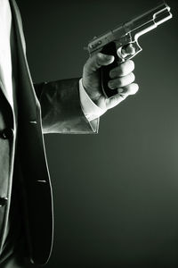 Midsection of man holding cigarette against black background