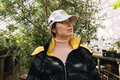 Portrait of young woman standing against plants