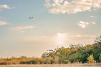 Airplane flying above trees on field against sky