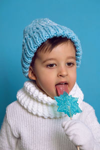 Baby boy eats a blue candy in the form of a snowflake