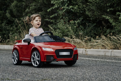 A girl riding a toy car