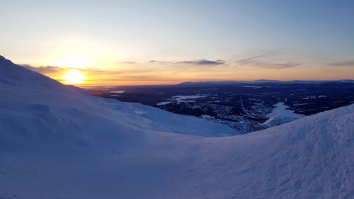 Scenic view of snow covered mountains against sky during sunset