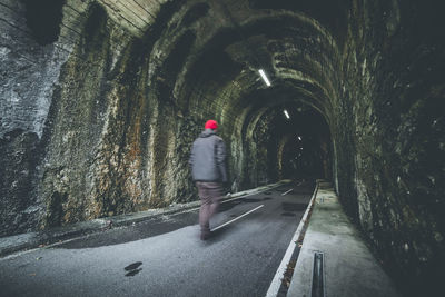 Rear view of man walking on tunnel road