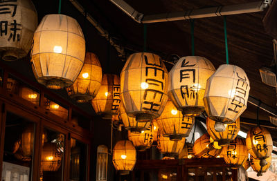 Low angle view of illuminated lanterns hanging by building