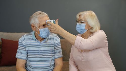 Woman checking husband temperature with thermometer