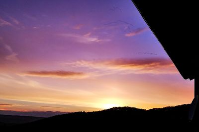 Low angle view of silhouette trees against dramatic sky