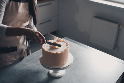 Woman making creamy birthday cake in kitchen closeup. holiday time. selective focus.