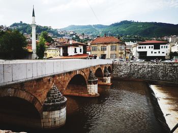 Arch bridge over river amidst buildings in town