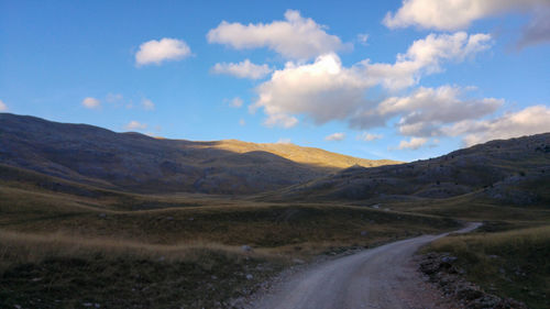 Road leading towards mountains against sky