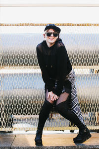 Portrait of young woman standing against chainlink fence.construction net. korean fashion. european.