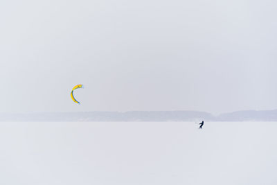 Person paragliding over sea against sky