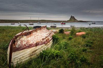 Abandoned boat in sea against sky