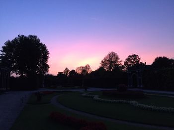 Trees on landscape against clear sky at sunset
