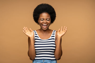 Portrait of young woman standing against yellow background