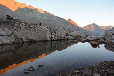 Granite rocks, ridgeline, and campsite reflected in alpine tarn at sunset