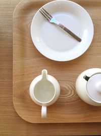 Directly above view of kettle by jug and plate in tray on table