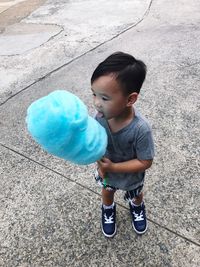 High angle view of boy eating cotton candy while standing on street