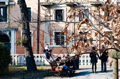 People on footpath against building in park during autumn