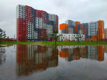 Reflection of buildings in lake against sky in city