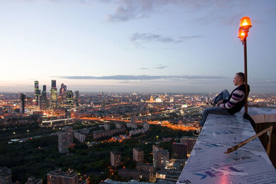 People standing by illuminated buildings against sky in city