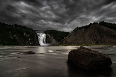 View of waterfall against cloudy sky