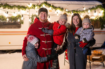 Portrait of happy family standing by motor home