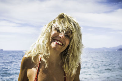 Portrait of smiling young woman against sea