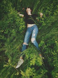 High angle view of young woman lying on plants at field