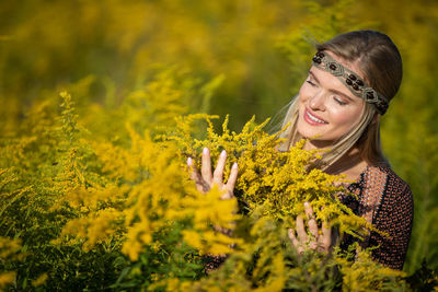 Portrait of young woman standing amidst plants on field